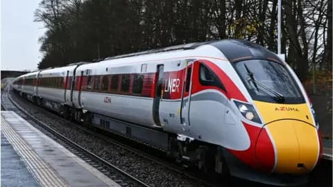 Modern Azuma train traveling on tracks through forest