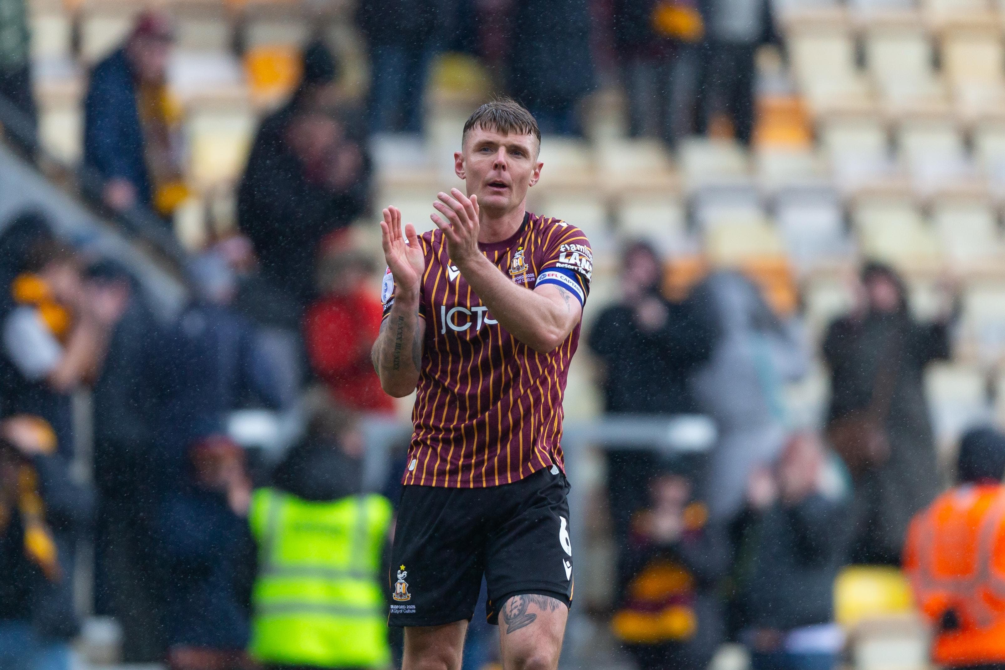 Soccer player clapping on a rainy day in a stadium