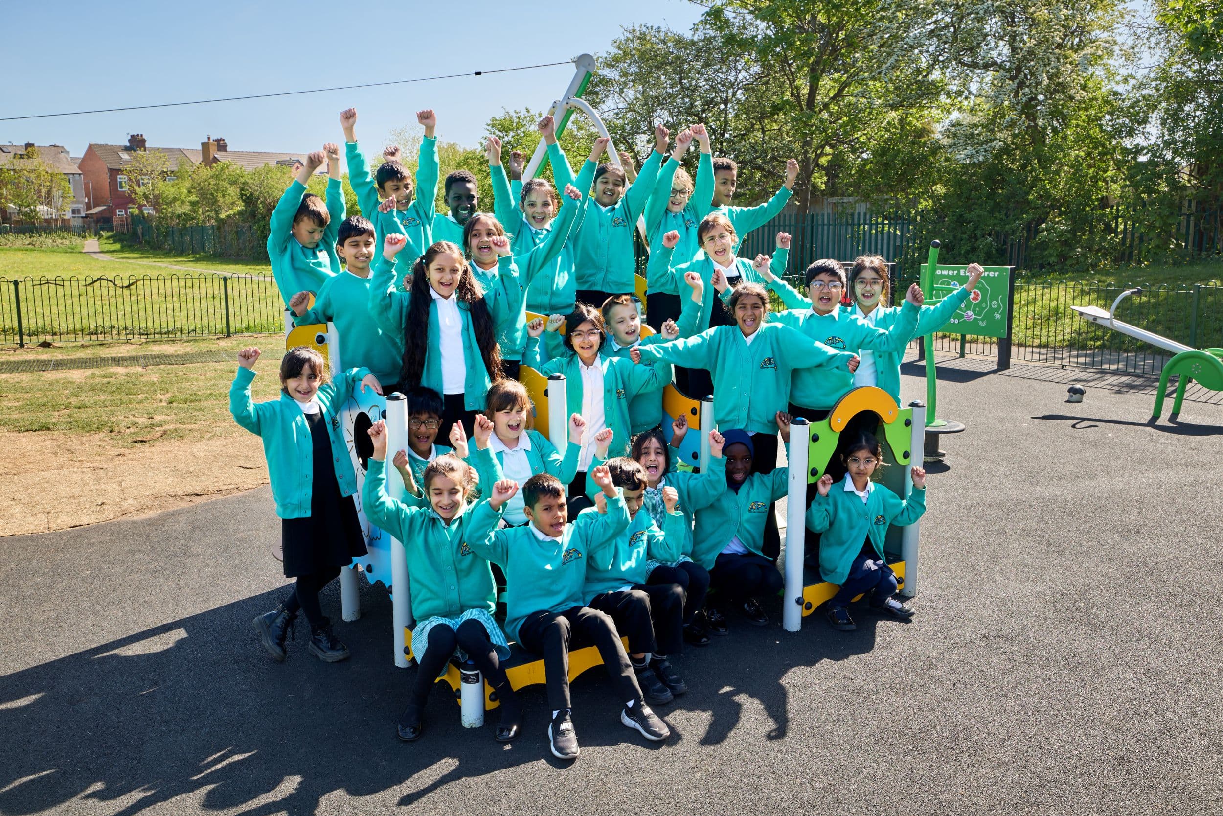 Group of schoolchildren in teal uniforms on playground equipment