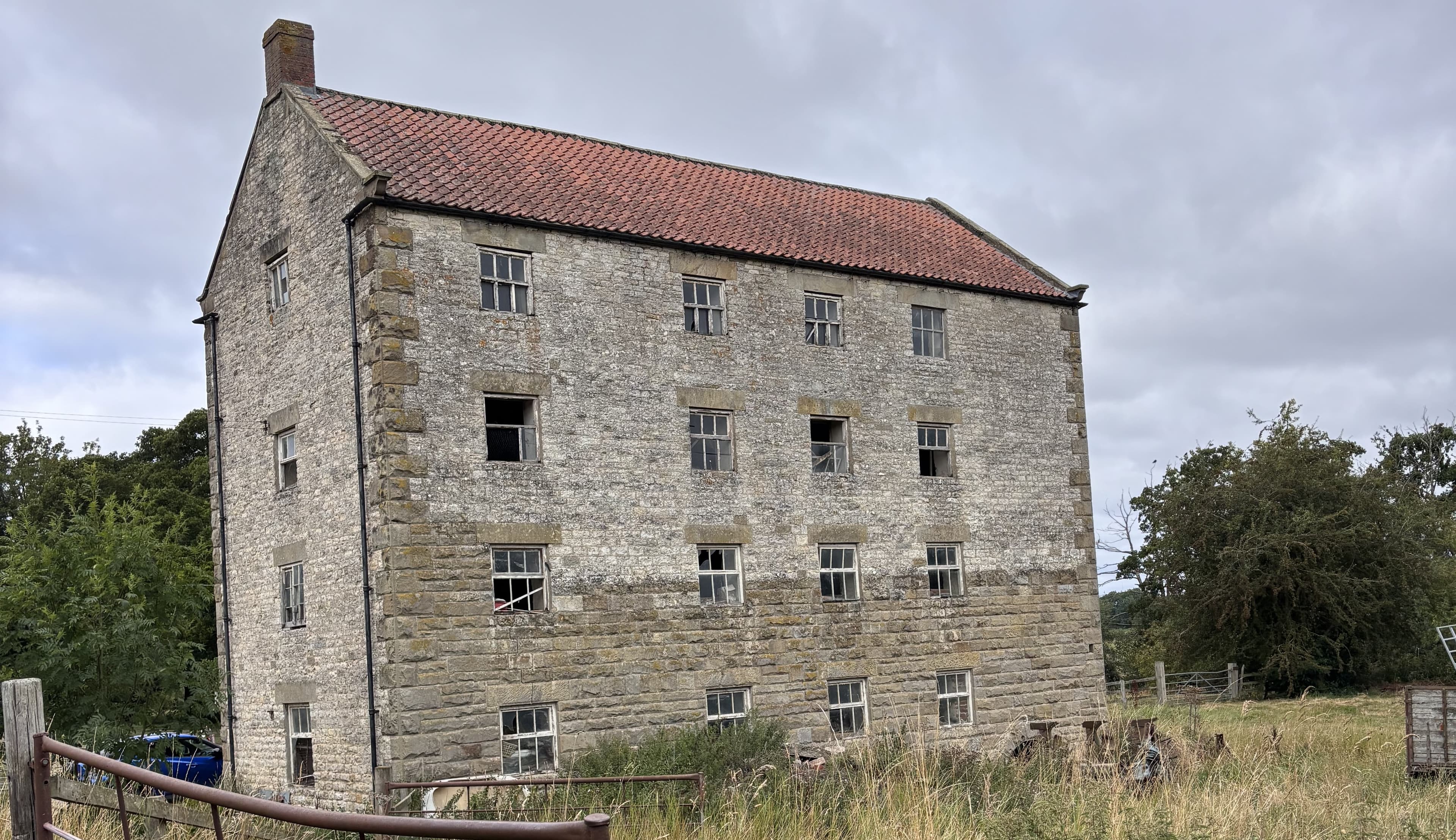 Historic stone mill with red-tiled roof in rural Yorkshire