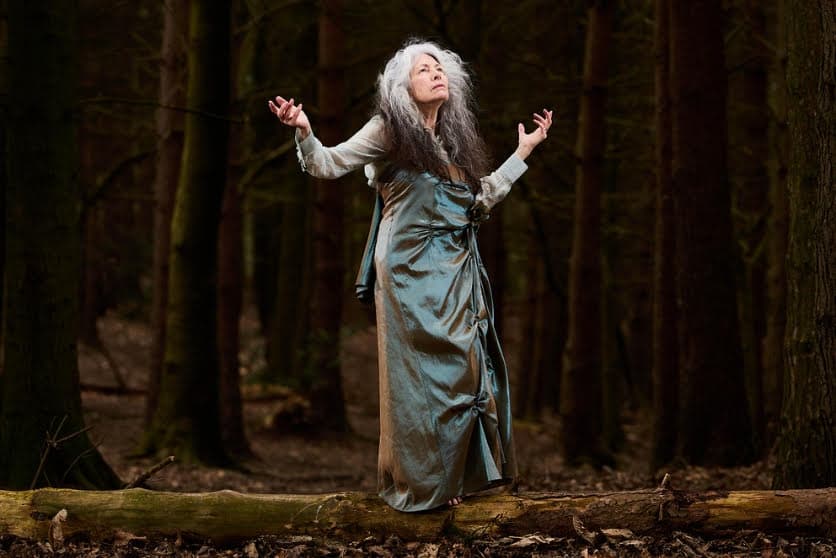 Woman in flowing gown with long hair in a dense forest