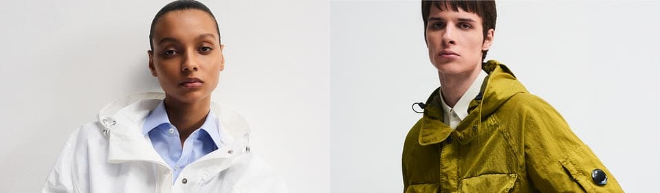 Two models in stylish raincoats against plain background