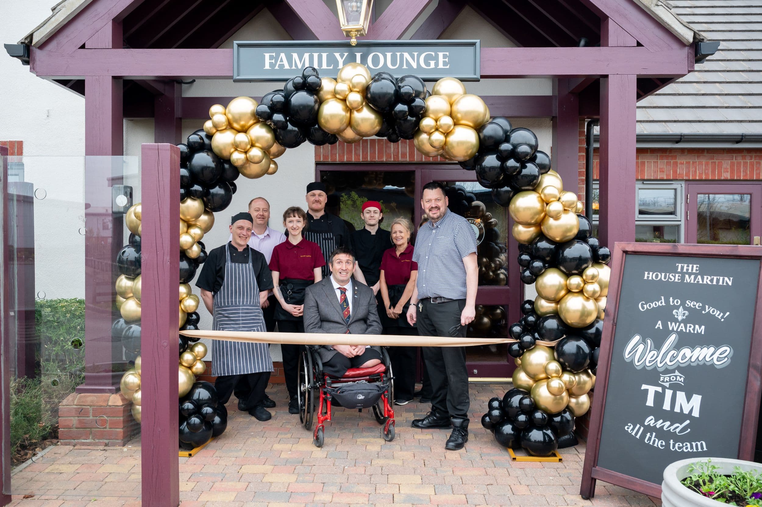 Group of people in front of pub entrance with balloon arch