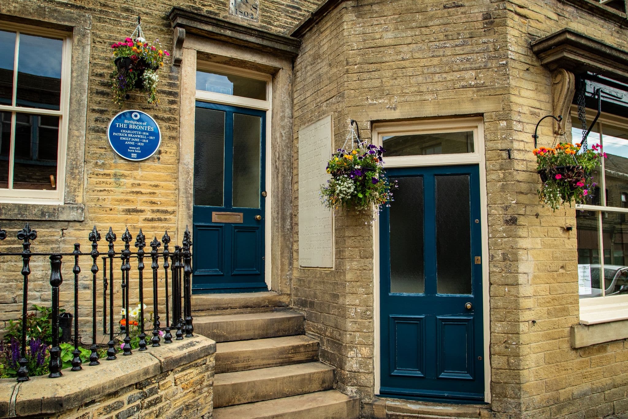 Historic stone building with blue door and floral baskets