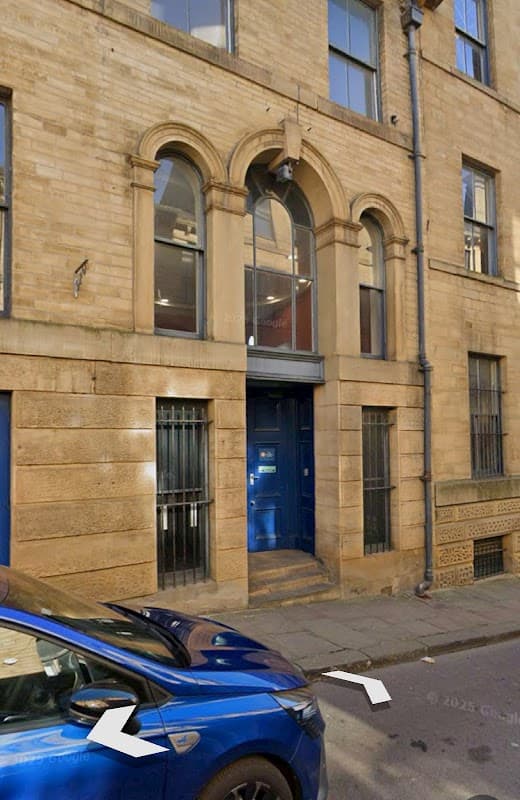 Pay & Display sign on Burnett Street, Bradford, with a stone building and blue car parked nearby.