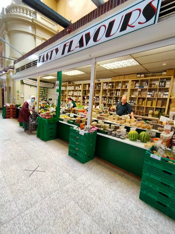 Vibrant market stall named "Tasty Flavours" displaying fresh produce and various goods in Doncaster Market.