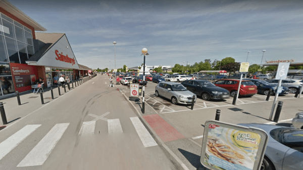 Pay & Display parking area outside Sainsbury's in Earswick, with cars parked and signage visible under clear skies.