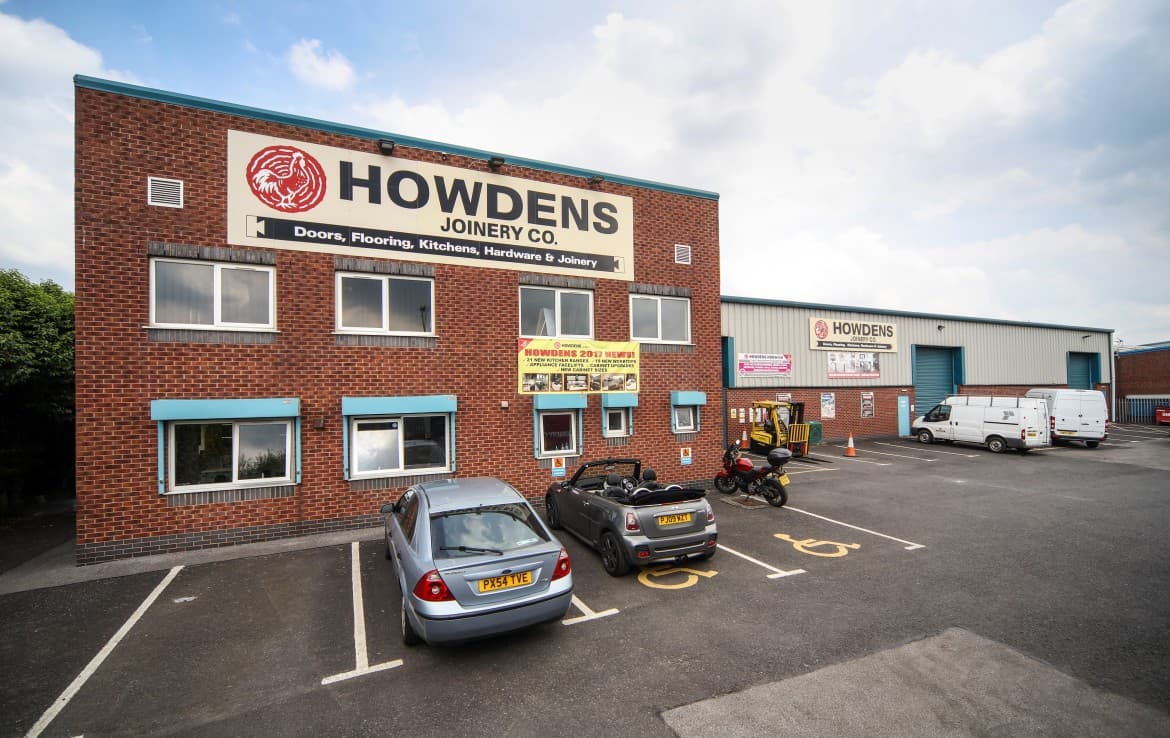 Howdens Joinery Co. building with parking lot, cars, and a delivery van in Eastwood, Yorkshire.