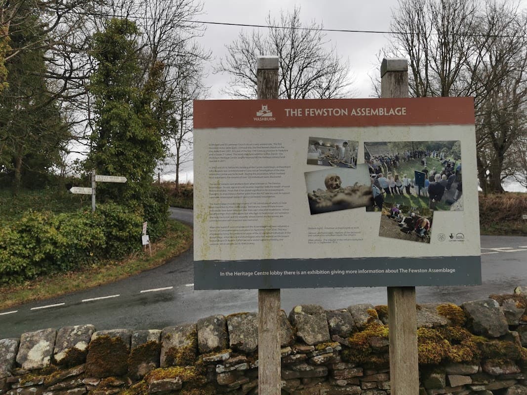 Signpost detailing "The Fewston Assemblage" with countryside backdrop and road intersection in Fewston, Yorkshire.