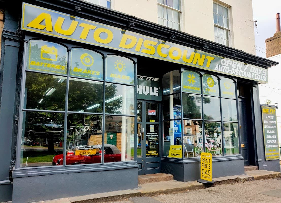 Bike shop storefront with large "AUTO DISCOUNT" sign, displaying services like batteries and brakes, in Harrogate.