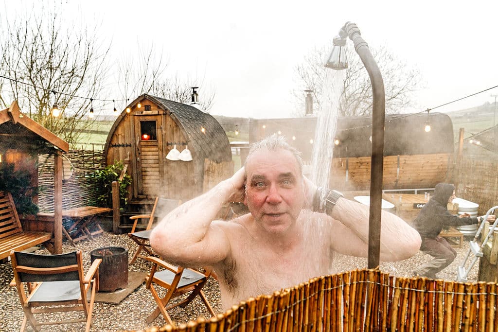 Man in outdoor shower at iglu sauna, Hebden Bridge