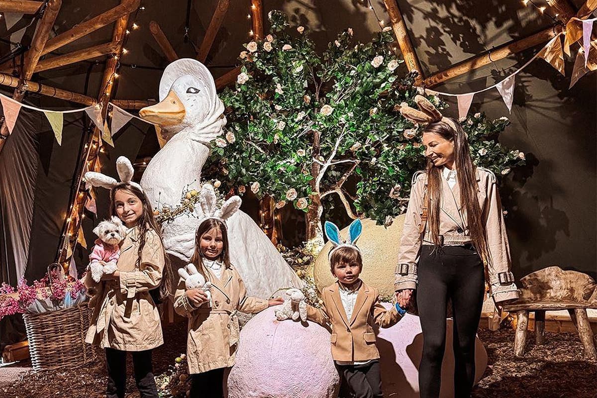 Family posing with large Mother Goose statue in a whimsical woodland setting