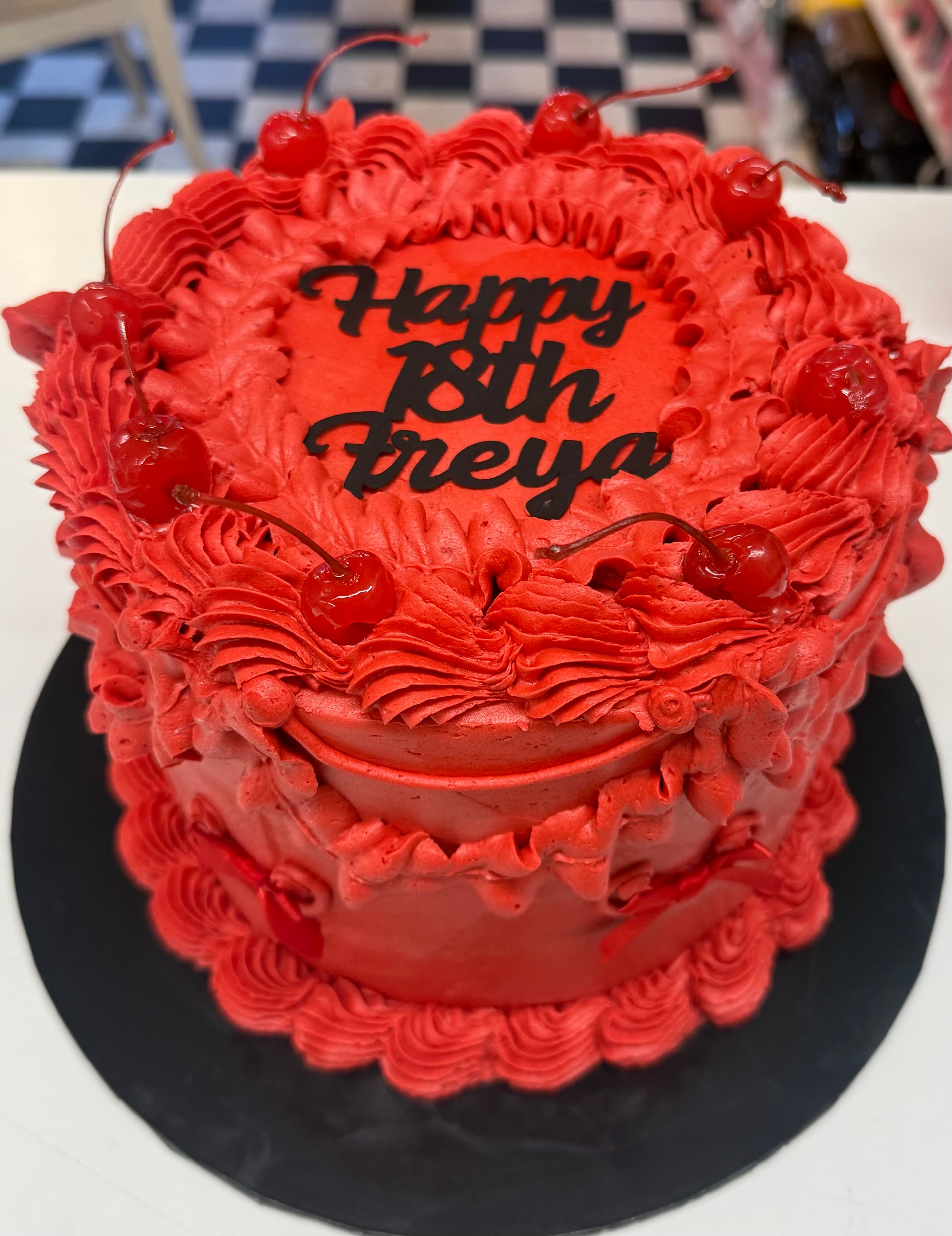 Vibrant red birthday cake with cherries and personalized icing