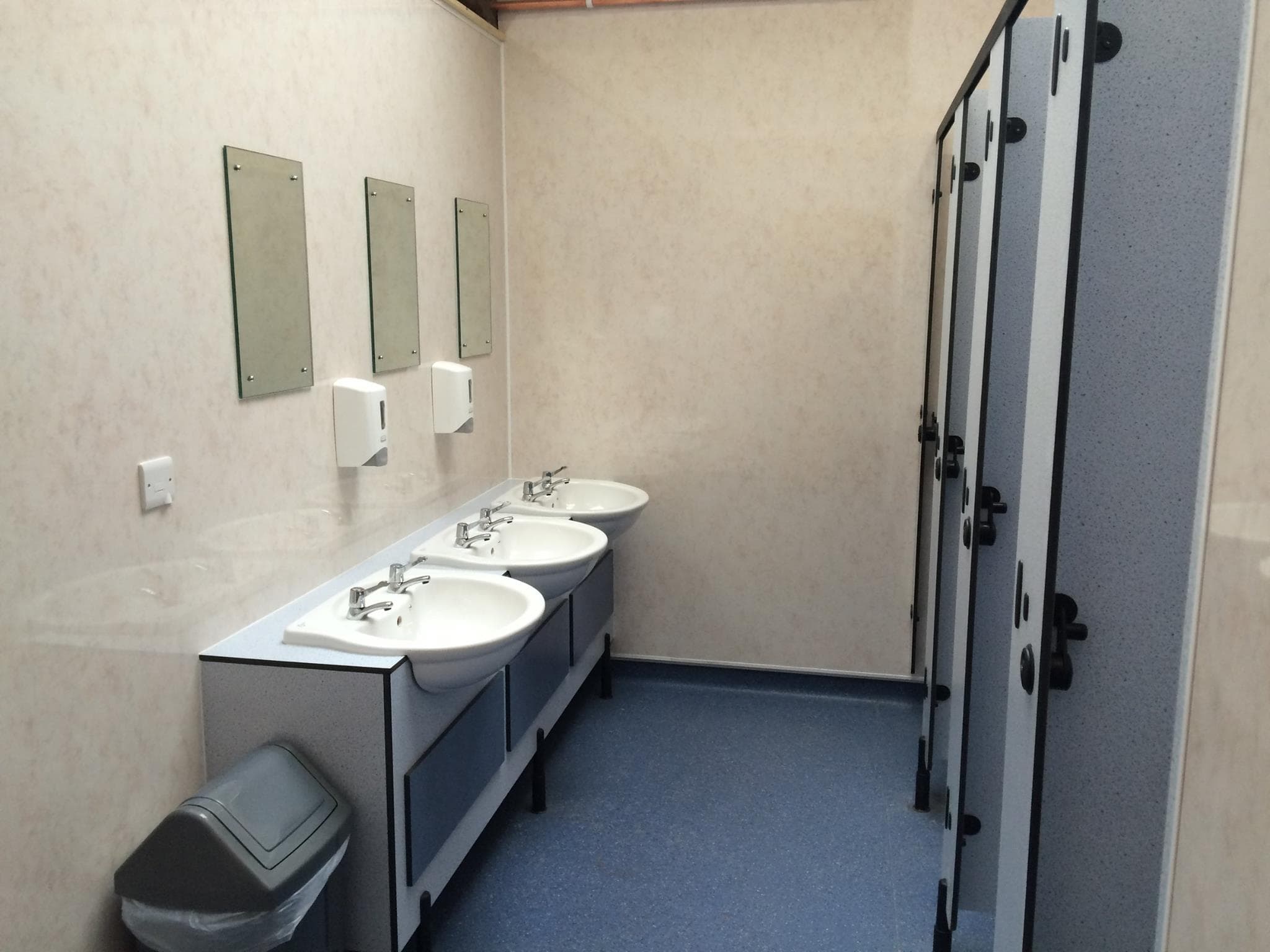 Clean campsite restroom with sinks, mirrors, and individual stalls