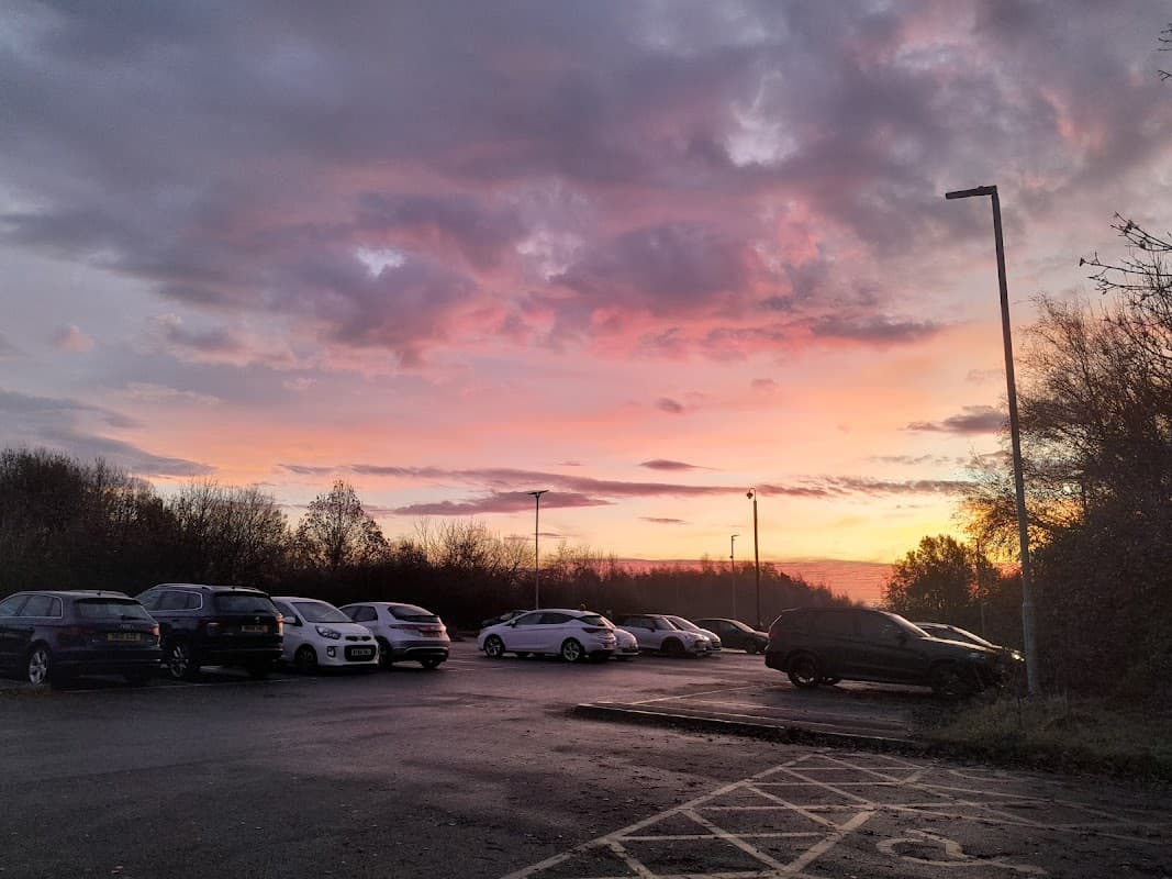 Fitzwilliam station car park at sunset, with parked cars and a colorful sky filled with clouds.