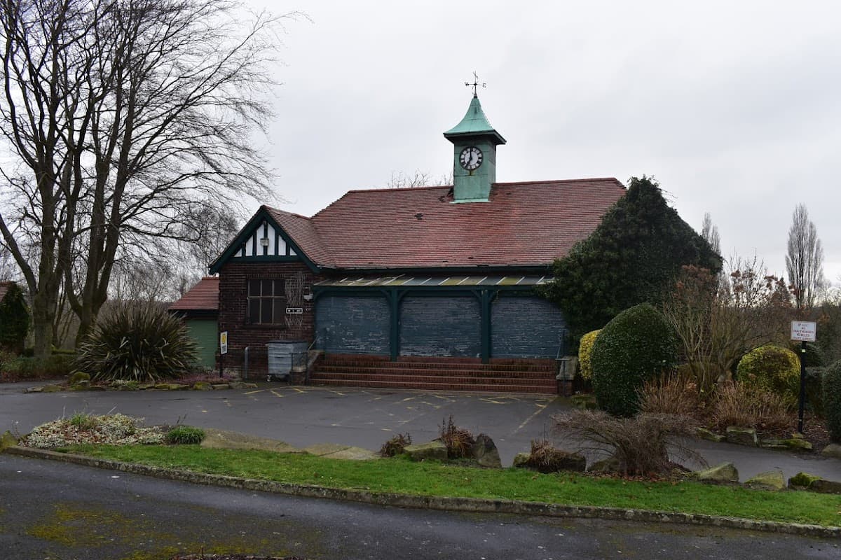 Historic building with a green clock tower, surrounded by landscaped gardens and a parking area in Kinsley, Yorkshire.