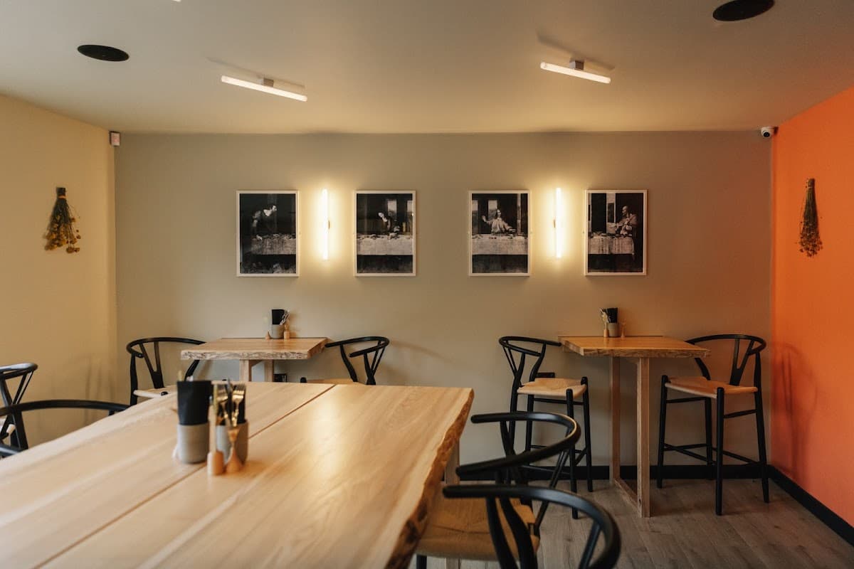 Stylish café interior with wooden tables, black chairs, and framed black-and-white photos on the wall.
