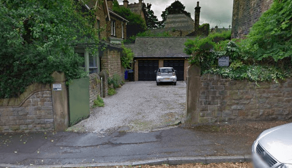 Gravel driveway leading to a garage, surrounded by stone walls and greenery in Nether Edge, Yorkshire.