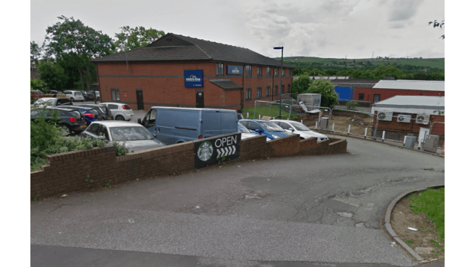 Pay & Display parking area with cars, a Starbucks sign, and a building in the background in Norristhorpe, Yorkshire.