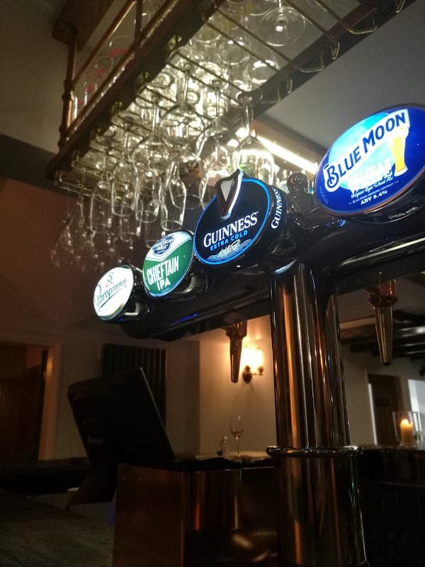 Bar counter with various beer taps, including Guinness and Chieftain IPA, and hanging glasses in the background.