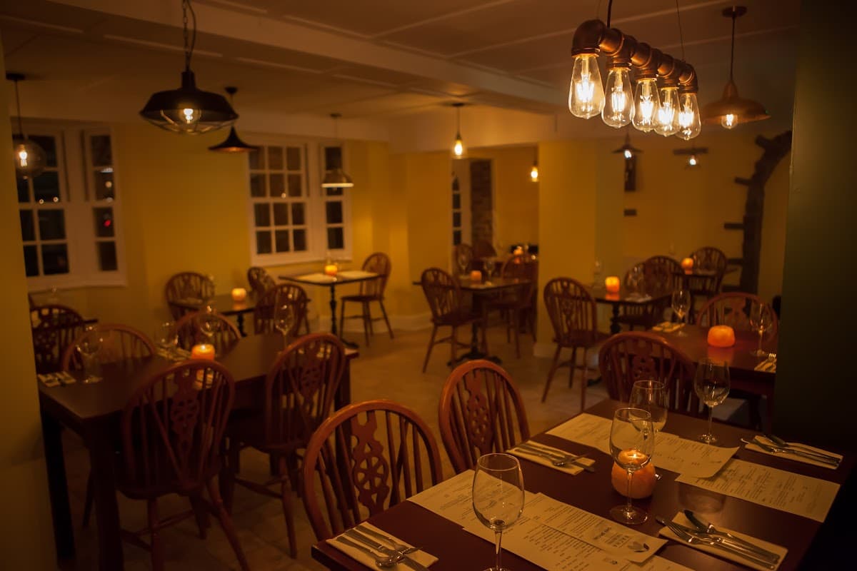 Cozy dining area with wooden tables, chairs, and warm lighting, creating an inviting atmosphere at Racha Thai Bistro.