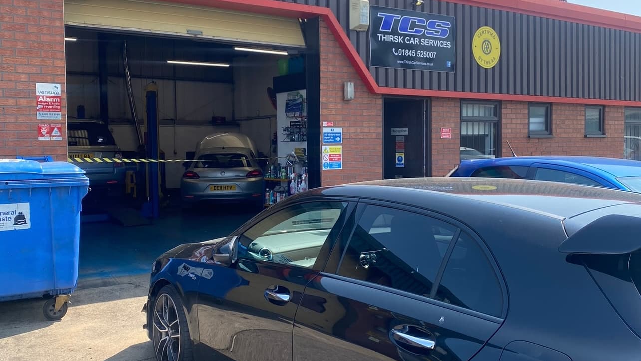 Thirsk Car Services building with a blue car outside, workshop area visible, and signage on the facade.