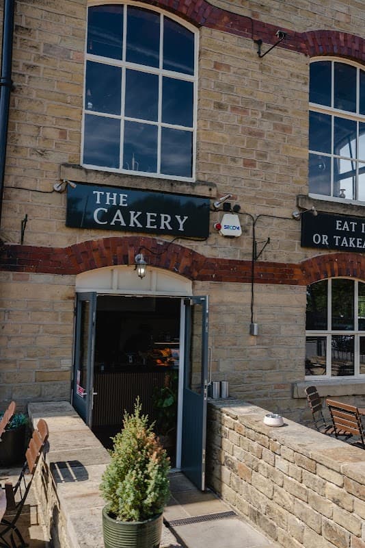The Cakery restaurant entrance featuring stone walls, large windows, and outdoor seating in West Vale, Yorkshire.