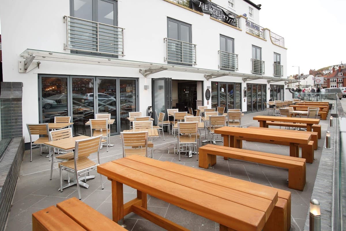 Modern bar exterior with outdoor seating, wooden tables, and large glass windows in Whitby, Yorkshire.