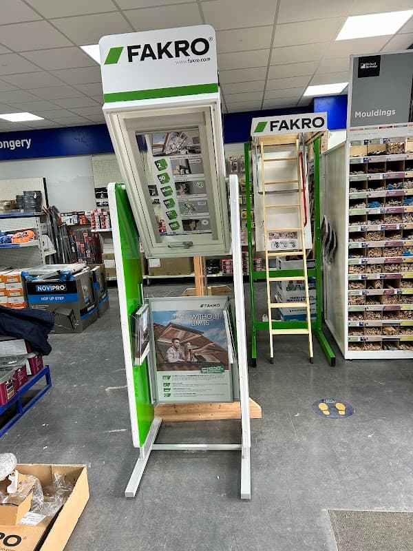 Display stand featuring FAKRO products, surrounded by shelves of ironmongery supplies in a retail setting.