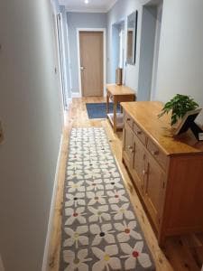 Hallway in Cherry Tree apartments, York, featuring a floral runner, wooden furniture, and light grey walls.