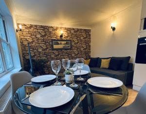 Cozy Harrogate cottage living room with stone accent wall, plush sofa, elegant dining setup, and soft ambient lighting.