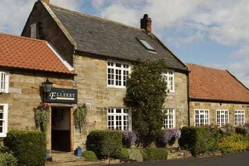 Charming stone country inn with white-framed windows, red-tiled roofs, and a quiet roadside setting.