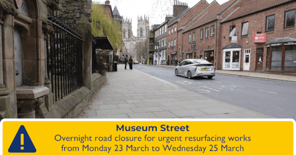 Museum Street in York, lined with historic buildings, features a road closure sign and a view of the Minster in the distance.
