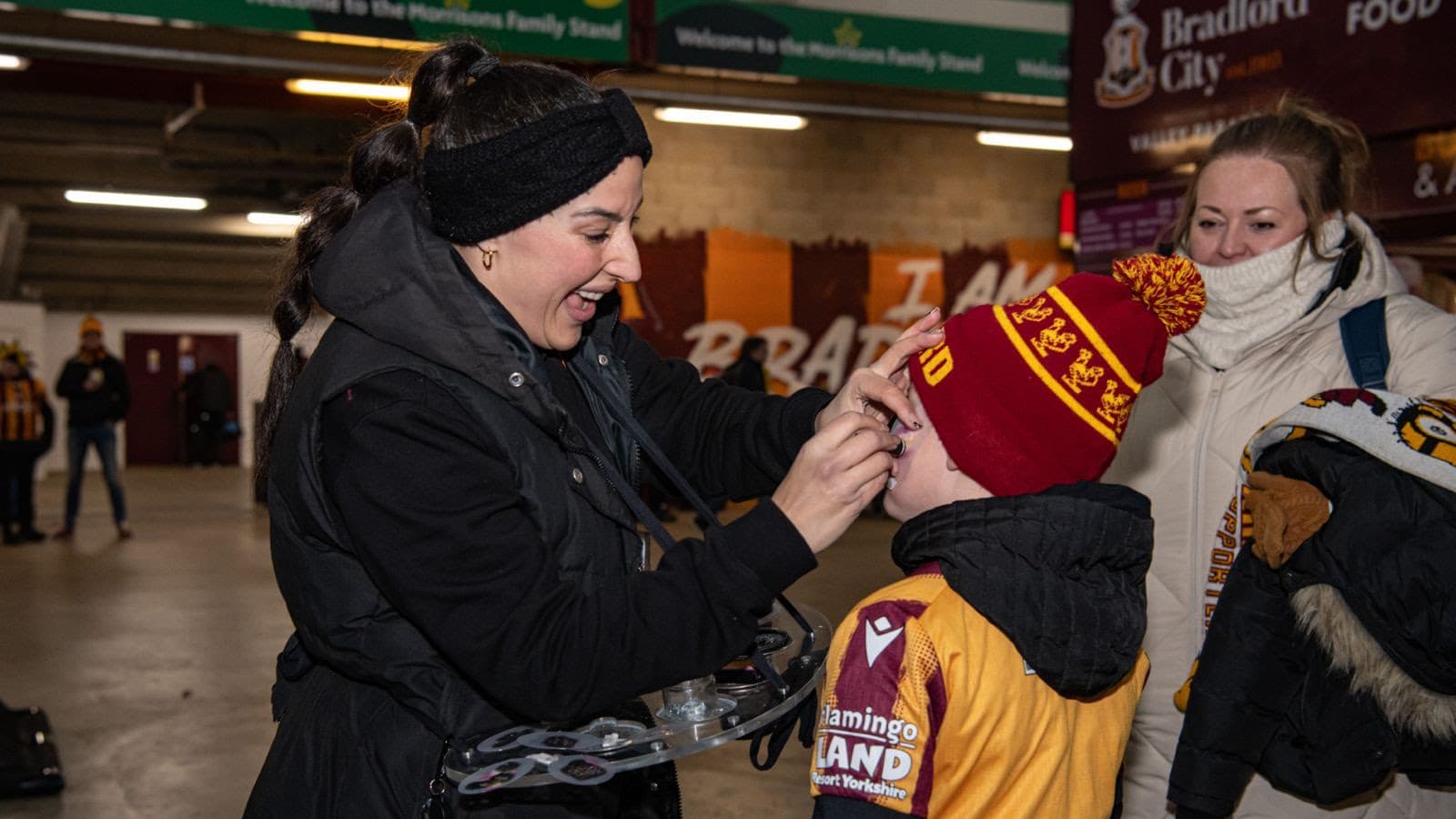 Woman assisting child wearing Bradford City football scarf