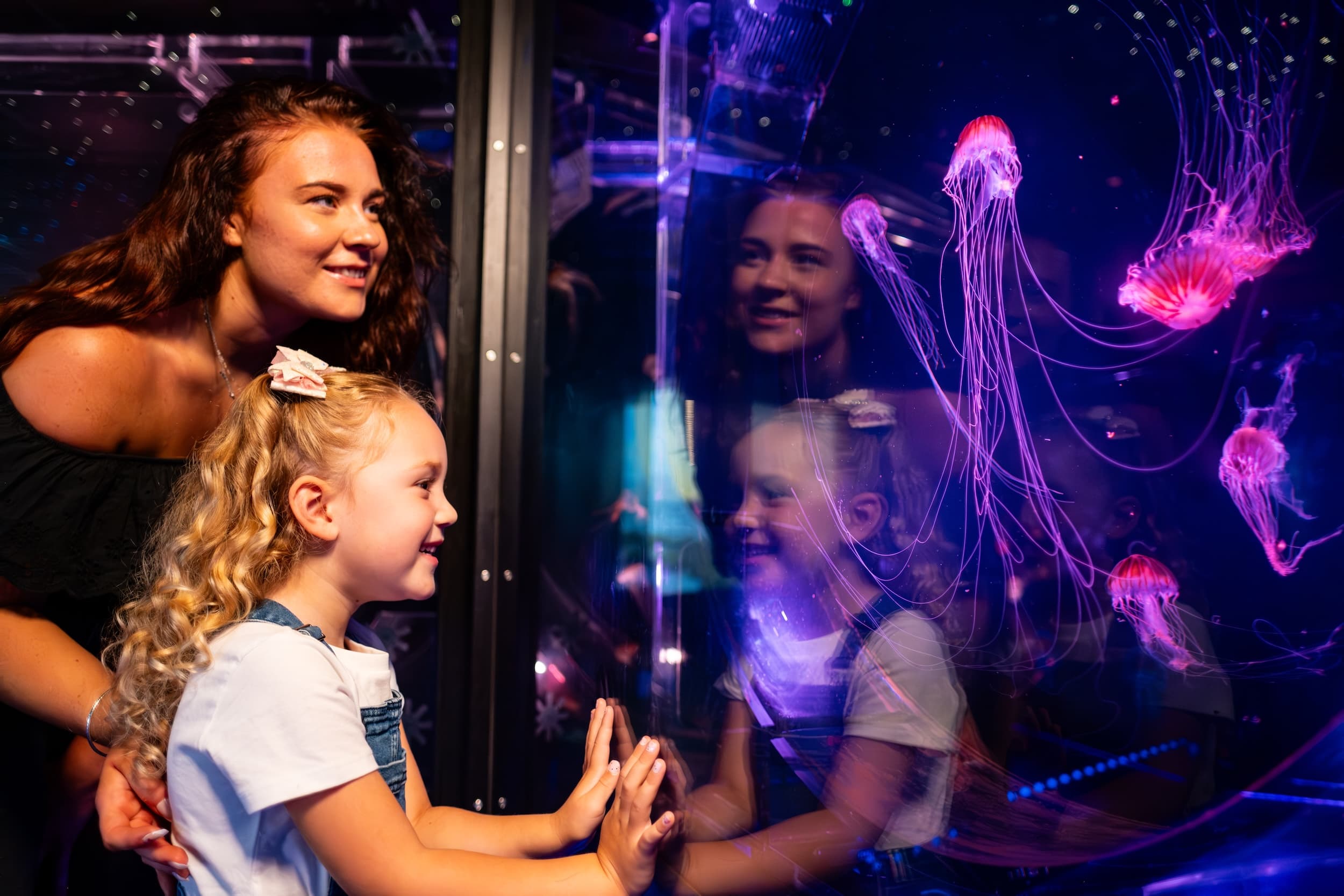 Mother and daughter enjoying colorful jellyfish display