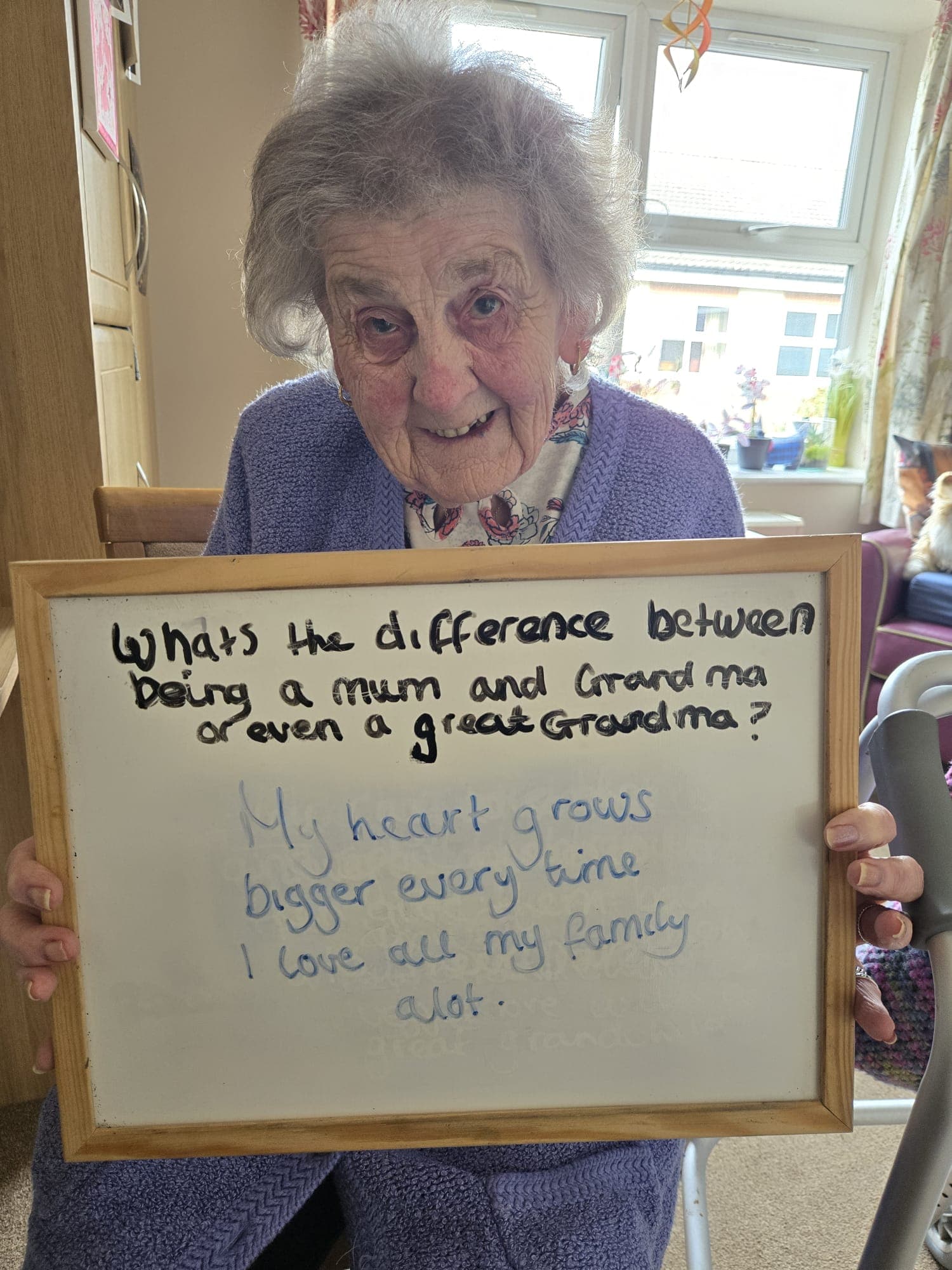 Elderly woman smiling while holding a whiteboard with a heartfelt message
