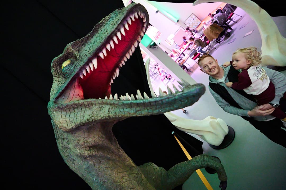 Life-sized dinosaur exhibit with visitors at a museum