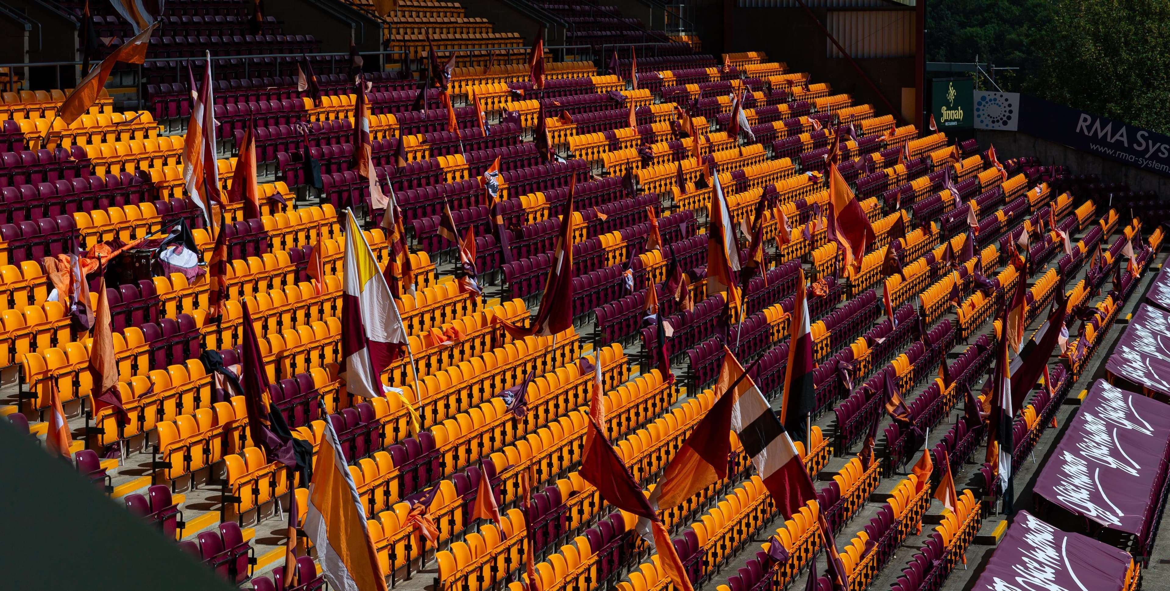 Empty stadium seats in claret and amber with flags waving