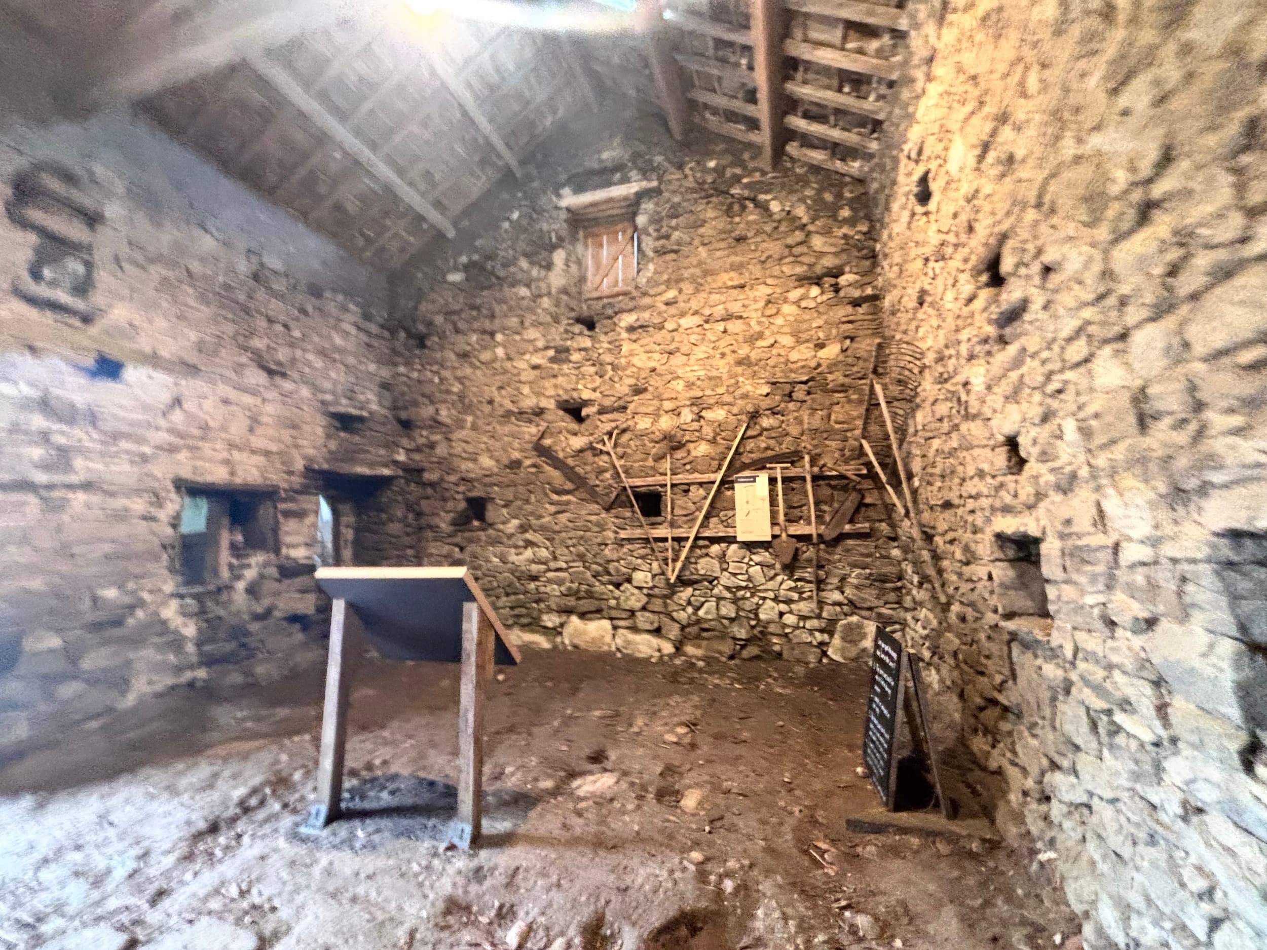 Rustic stone barn interior with wooden beams and display boards