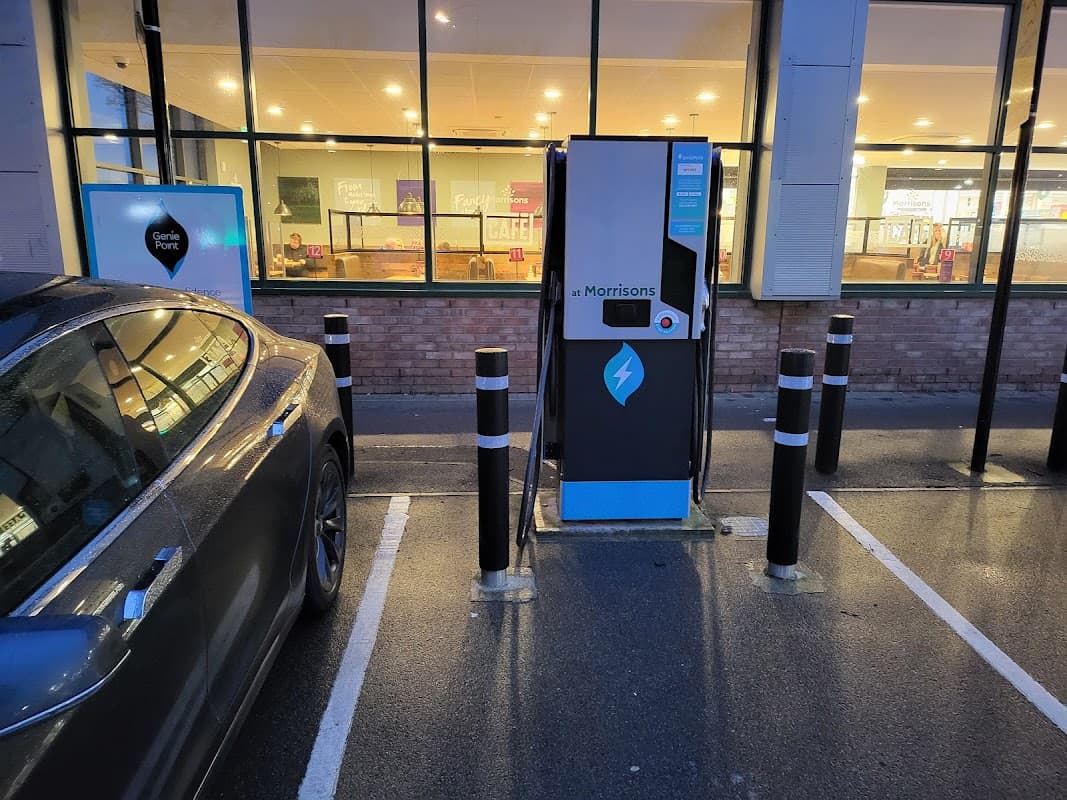 GeniePoint electric vehicle charging station next to a parked car, with a café visible in the background.