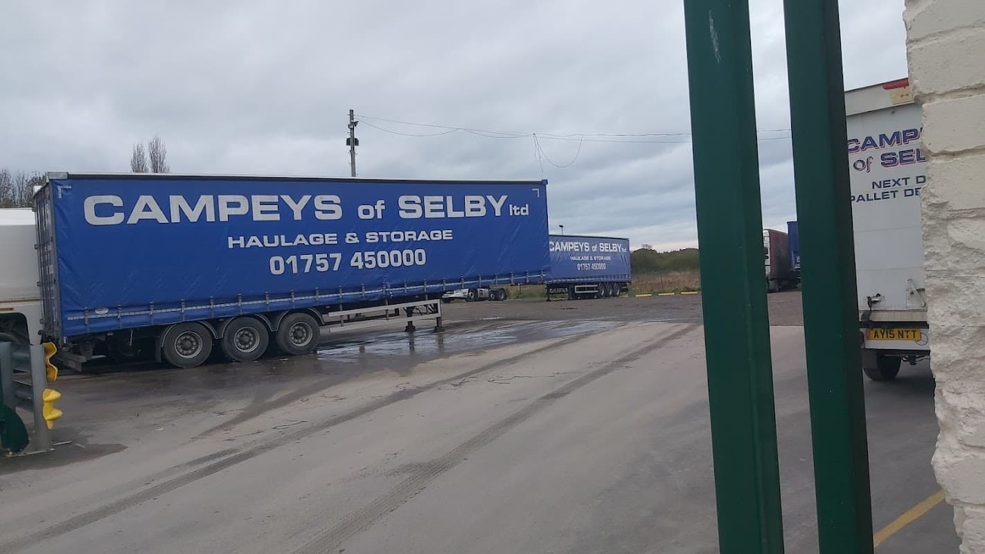 Large blue trailers with "Campeys of Selby" signage parked in a car park, cloudy sky in the background.