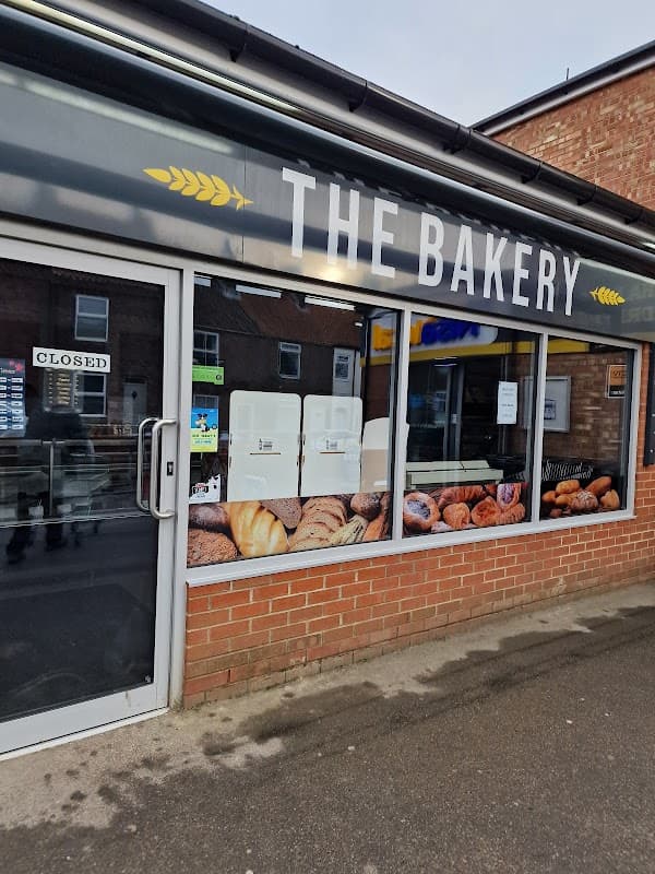 Shopfront of Nisa Local with a bakery sign, featuring a display of various baked goods. Door shows "CLOSED" sign.