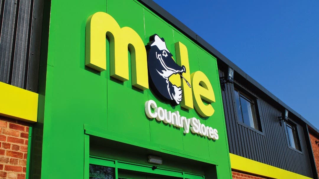 Bright green storefront with "mole Country Stores" sign featuring a cartoon mole, under a clear blue sky.