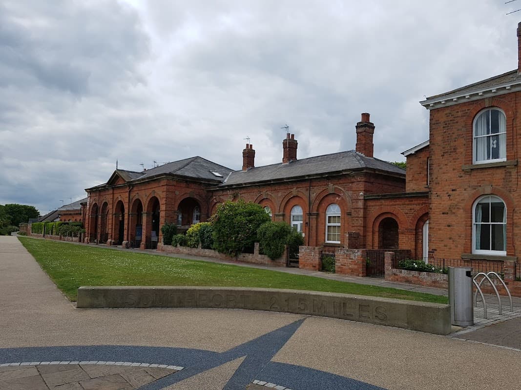 Sands Lane parking area with brick buildings, arched entrances, and a stone sign for Doncaster 15 miles ahead.