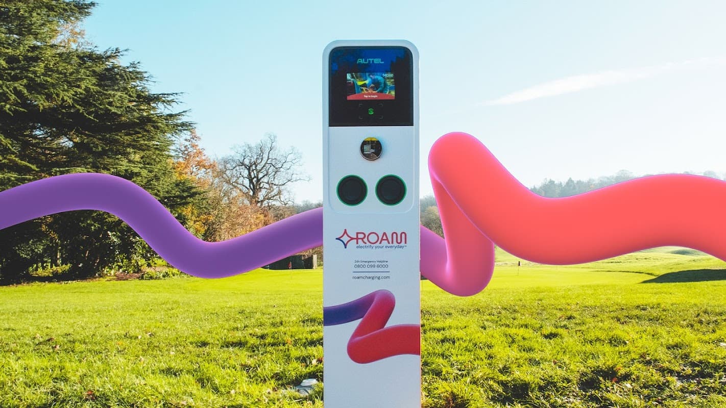 Charging station with a digital display, set in a green landscape with colorful abstract shapes around it.