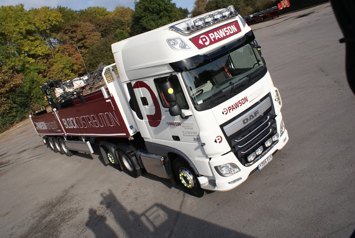 White DAF truck with "Pawson Transport" branding, parked in a lot with trees in the background.