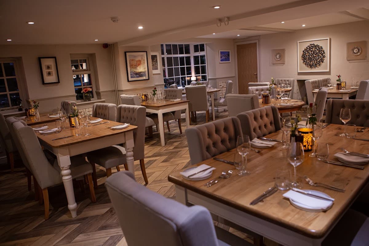 Cozy dining area with wooden tables, upholstered chairs, and soft lighting, creating a warm atmosphere.