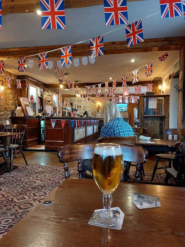 Interior of Poachers Barn bar with Union Jack bunting, wooden furniture, and a glass of beer on a table.