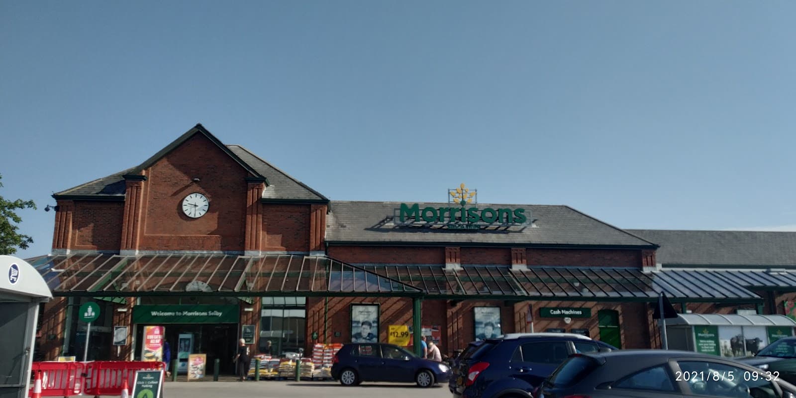 Morrisons store in Selby, Yorkshire, featuring a clock tower and large glass entrance with shopping carts outside.