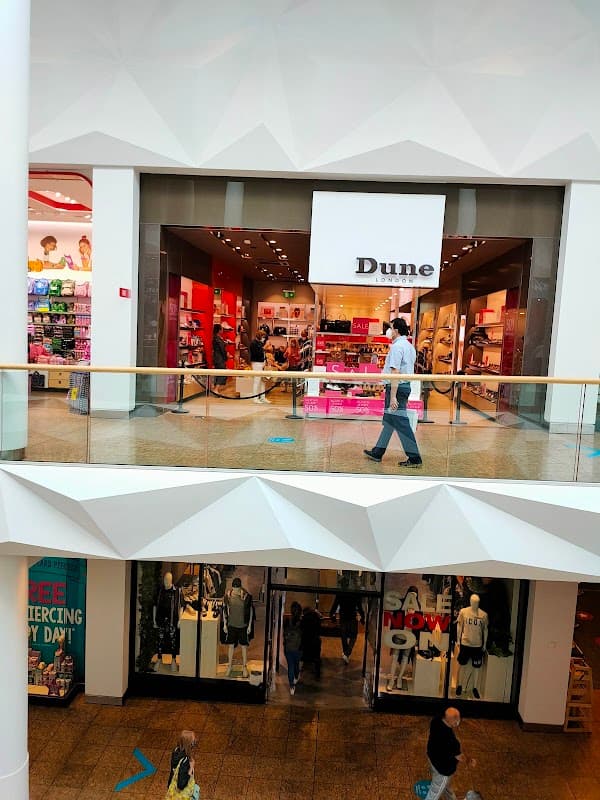 Shoe shop "Dune" in a mall, featuring bright displays and shoppers browsing inside.
